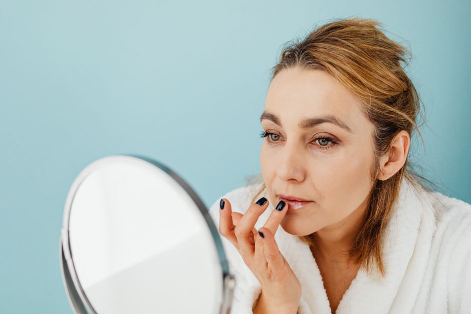 woman applying lip balm - healthy winter skin woman applying lip balm - healthy winter skin