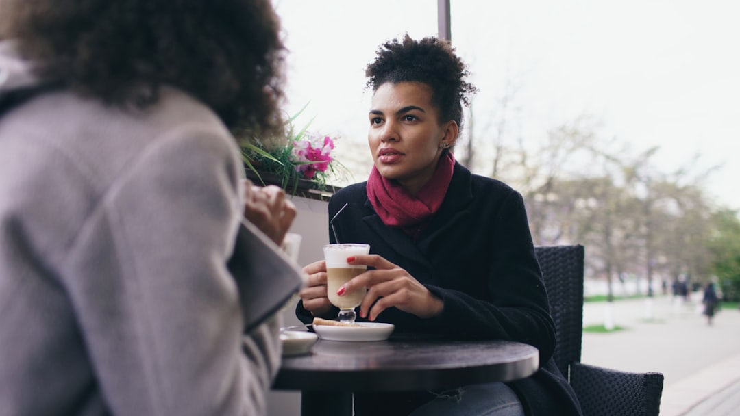 A woman talking to a supportive friend over coffee - postnatal depression support