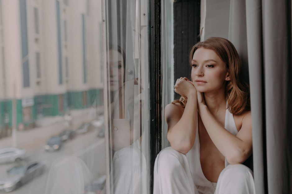 woman reflecting by a window about her relationship status