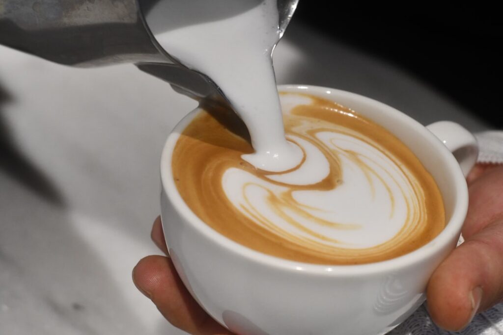 Espresso swirling into creamy milk and golden banana syrup