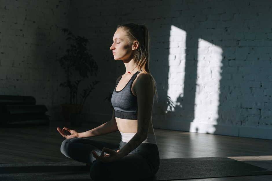A woman practicing deep breathing in a cozy, peaceful bedroom setting A woman practicing deep breathing in a cozy, peaceful bedroom setting
